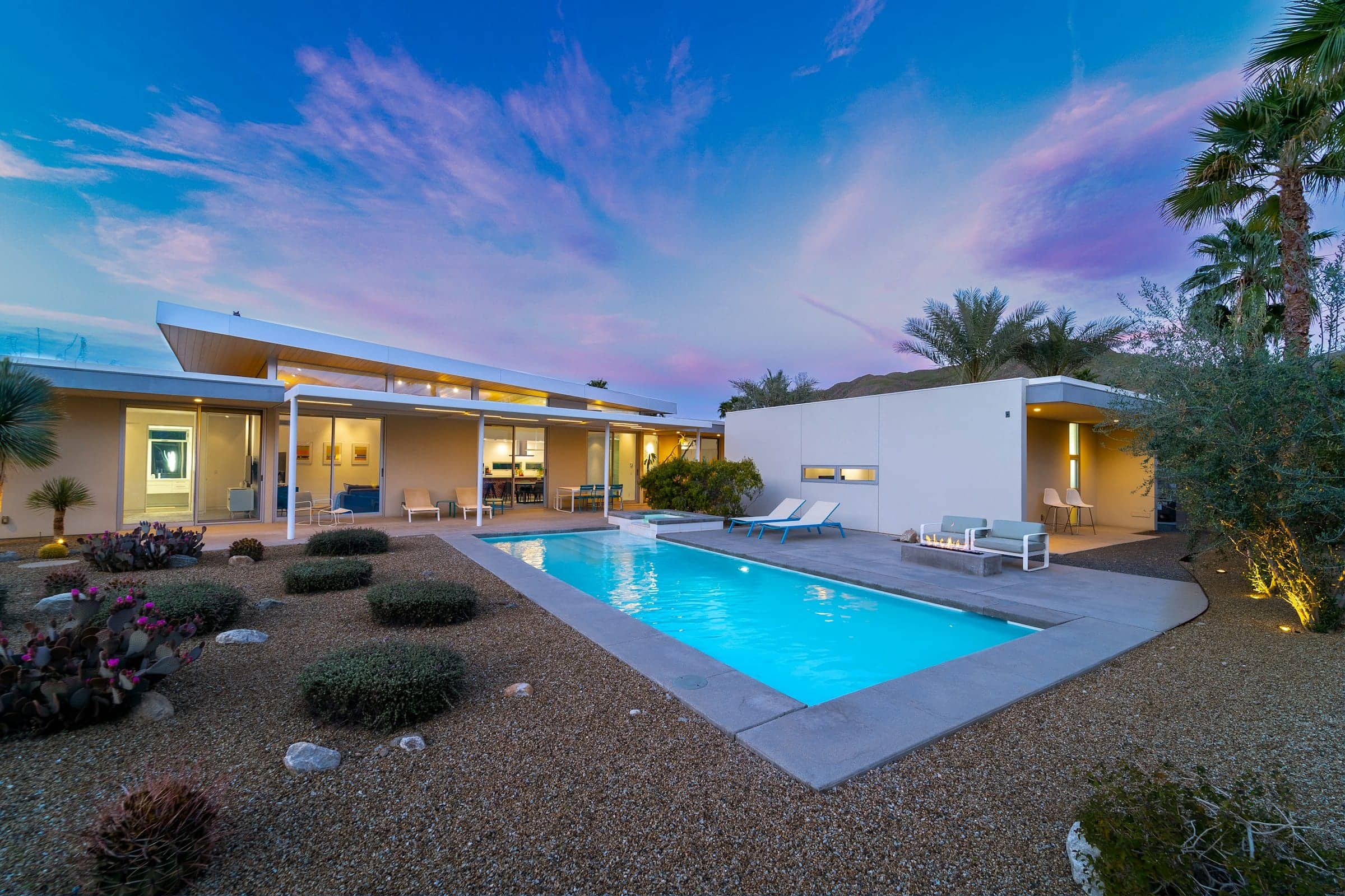 A low modern house and pool at dusk with desert landscaping