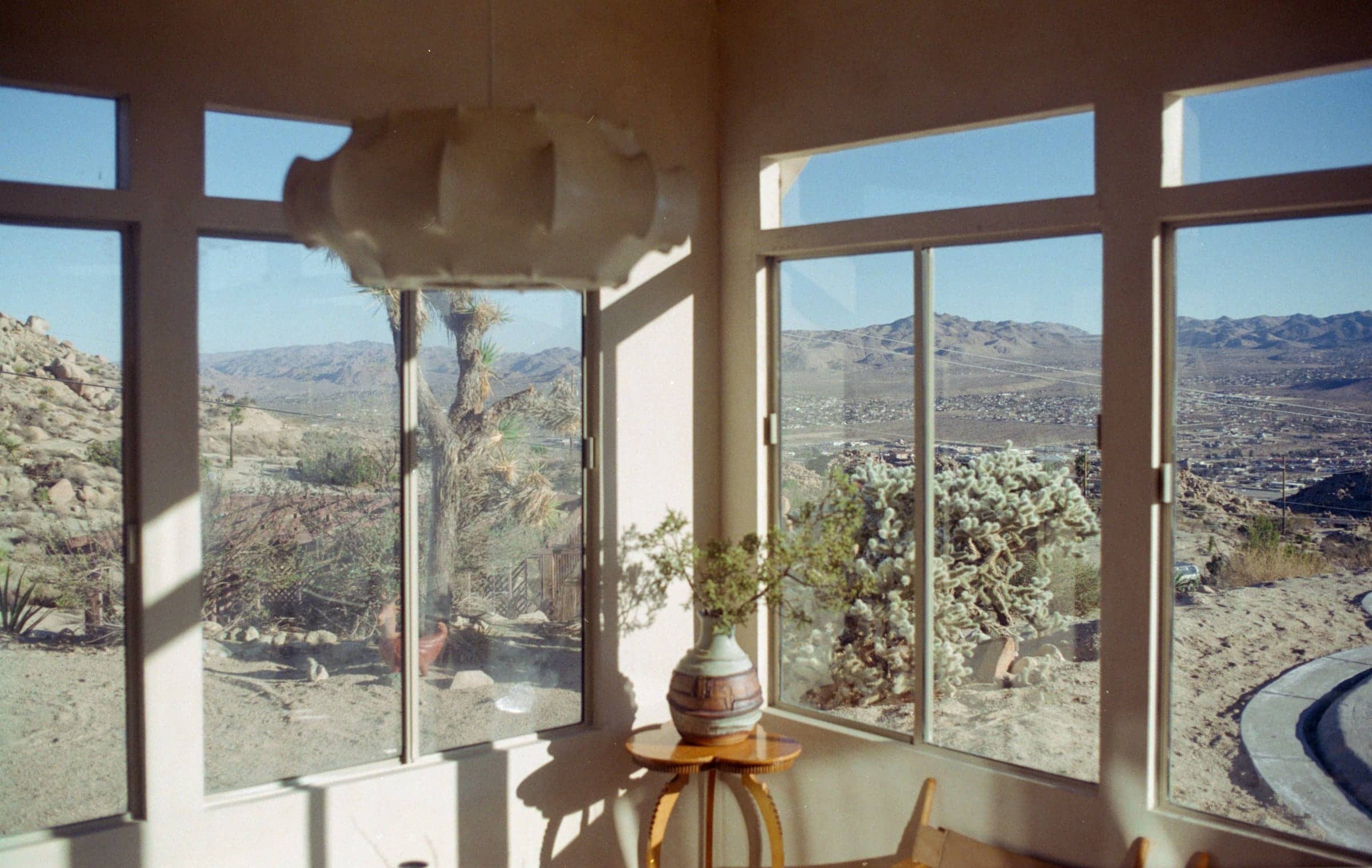 A sunlit corner with a paper lantern and a vase, framed by windows onto the high desert